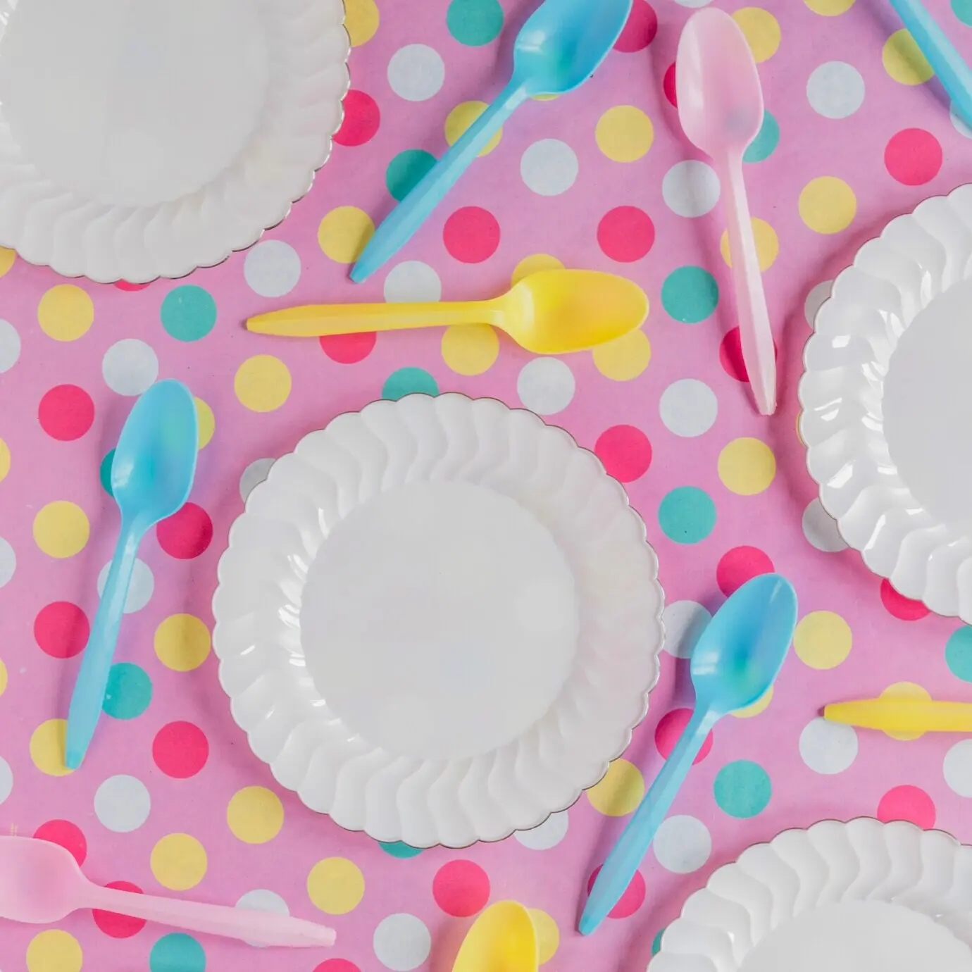 На разноцветной поверхности — белые тарелки.